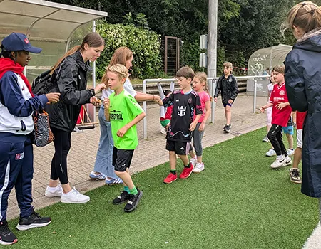 Kinder nehmen Gummibänder als Zählmittel beim Spendenlauf entgegen