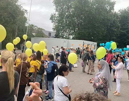 Eltern und Schüler:innen lassen Luftballons auf dem Schulhof fliegen