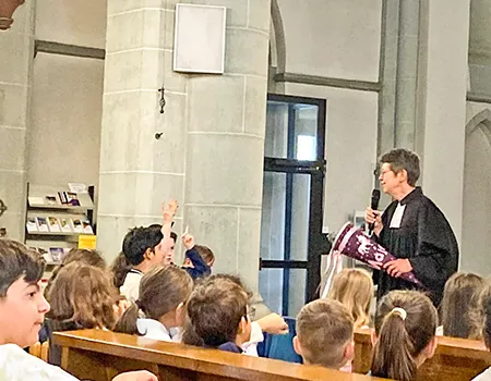 Geistliche führt mit Kindern in der Kirche ein Gespräch