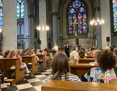 Schüler:innen sitzen in der Kirche und folgen dem Gottesdienst