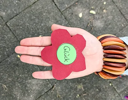 Kartonblume mit der Aufschrift Glück für die Viertklässler auf einer Hand