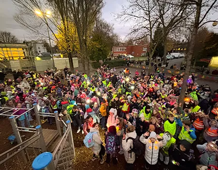 Eine große Gruppe Kinder steht mit Leuchtwesten auf dem Schulhof