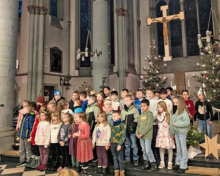 Eine große Gruppe Kinder trägt in der Kirche ein Lied im Gottesdienst vor