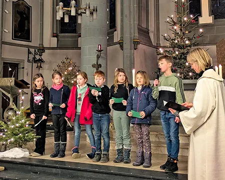 Eine  Gruppe Kinder trägt in der Kirche vorbereitete Texte vor