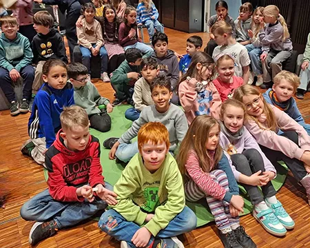 Kinder sitzen im Musikforum auf dem Boden